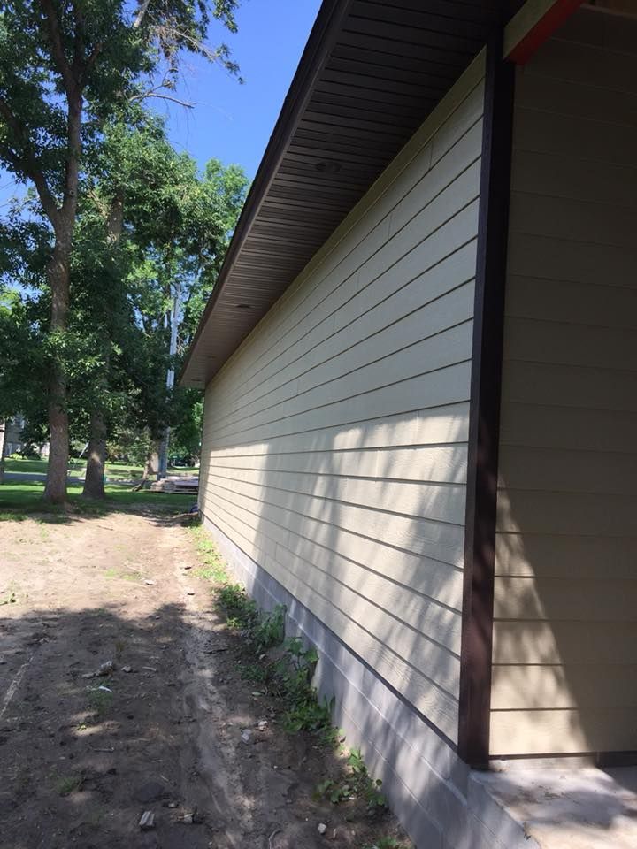A house with a lot of siding and trees in the background