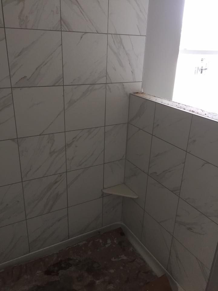A bathroom with white tiles and a window