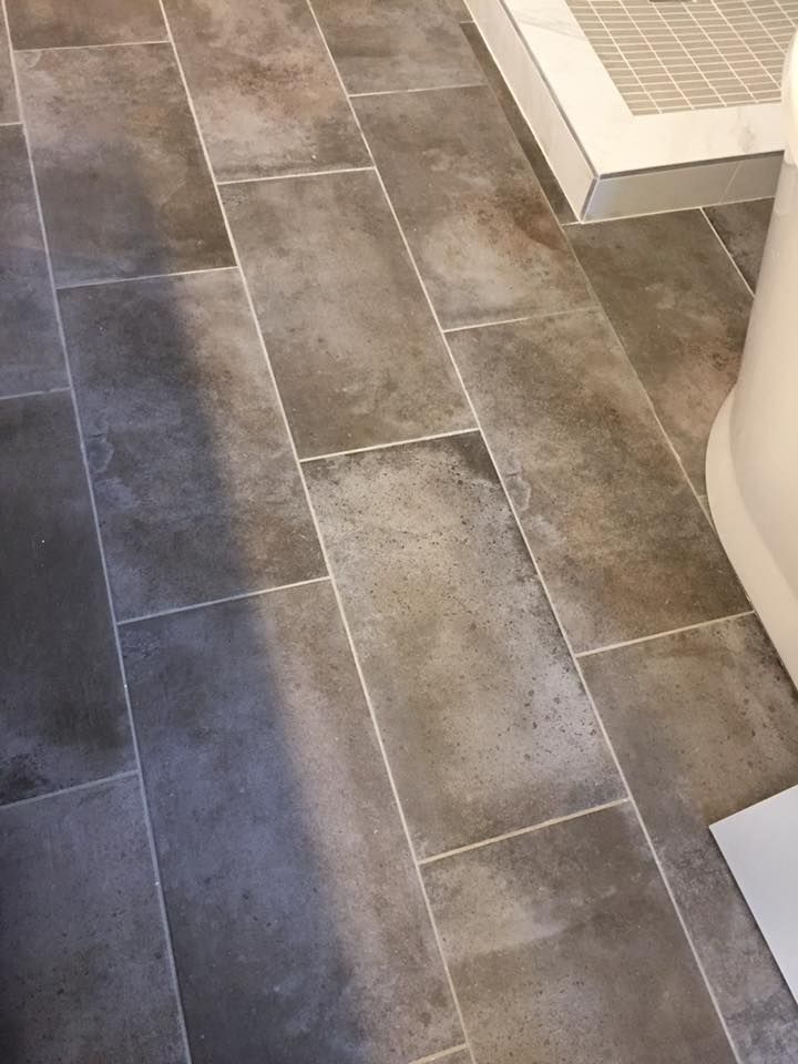 A close up of a tiled floor in a bathroom next to a toilet.