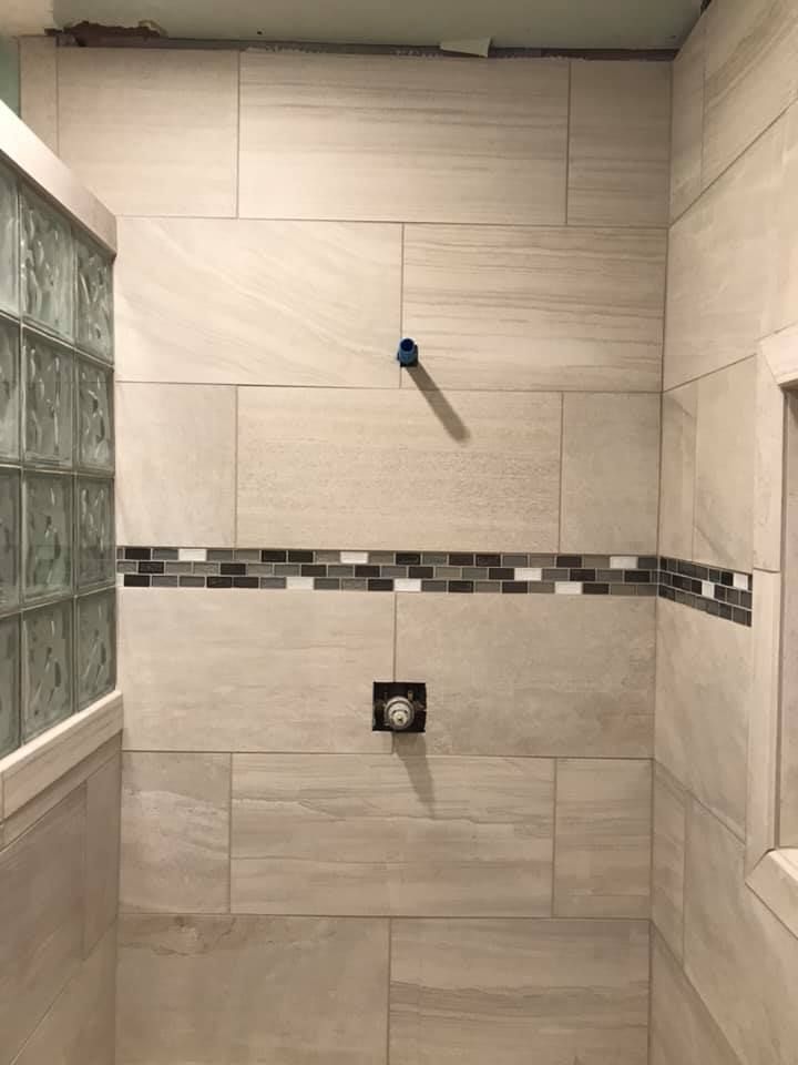 A bathroom with tiled walls and a shower head.