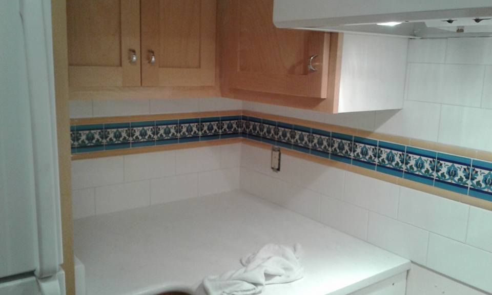 A kitchen with wooden cabinets and white tiles.