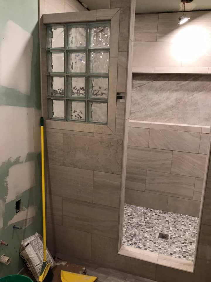A bathroom with a glass block wall and a walk in shower.