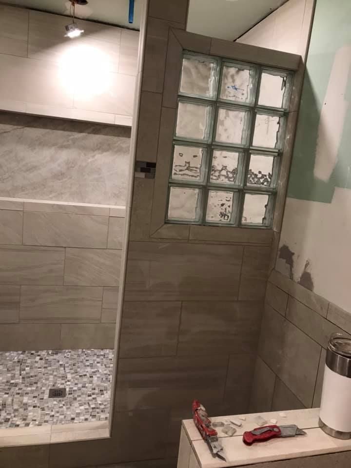 A bathroom with a walk in shower and a glass block door.