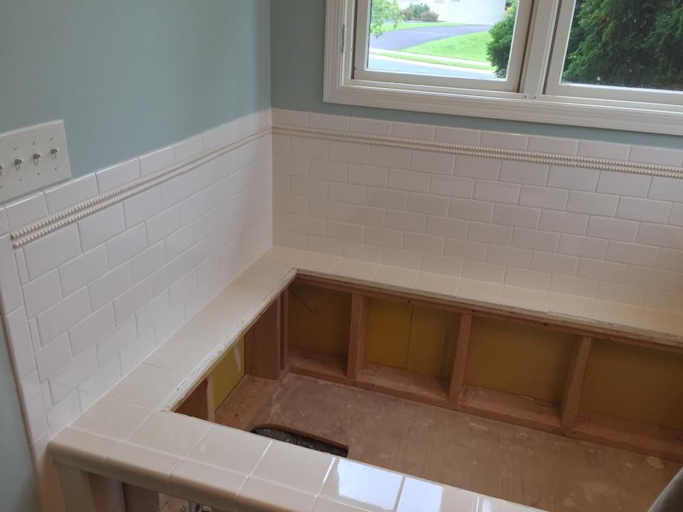A bathroom with a window and a bench in the corner