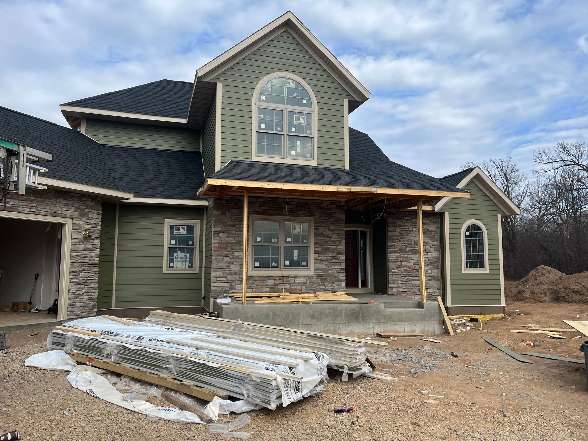 A red truck is parked in front of a house under construction.