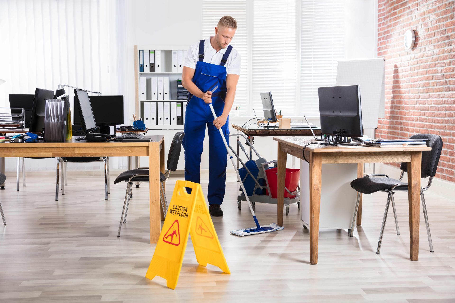 a man is cleaning the floor of an office with a mop