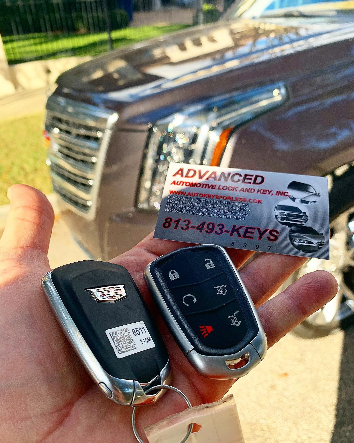 A person is holding two car keys in front of a car.