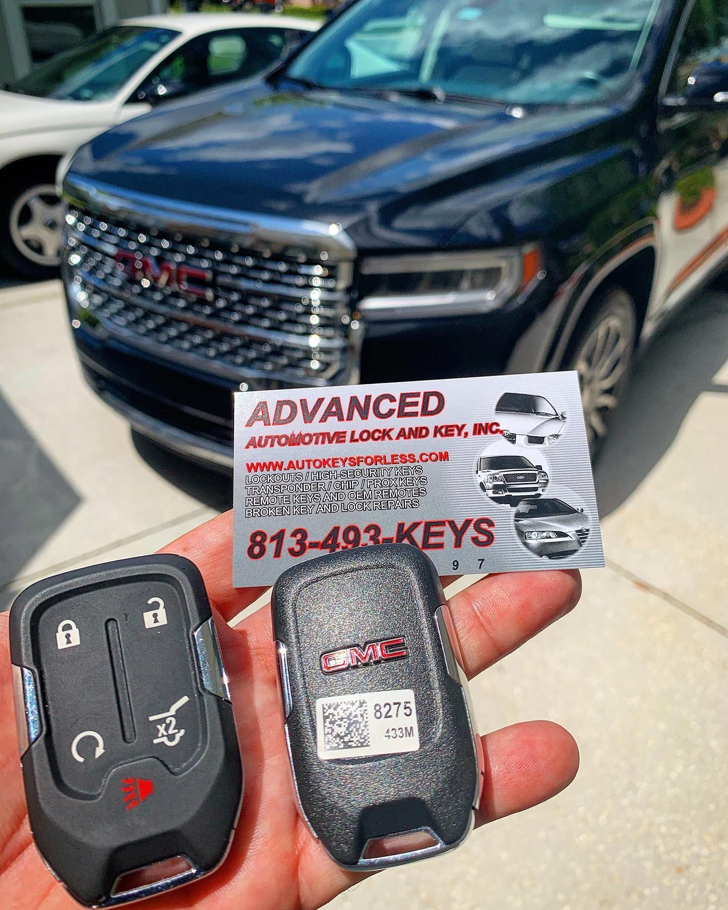 A person is holding a gmc remote control in front of a car.