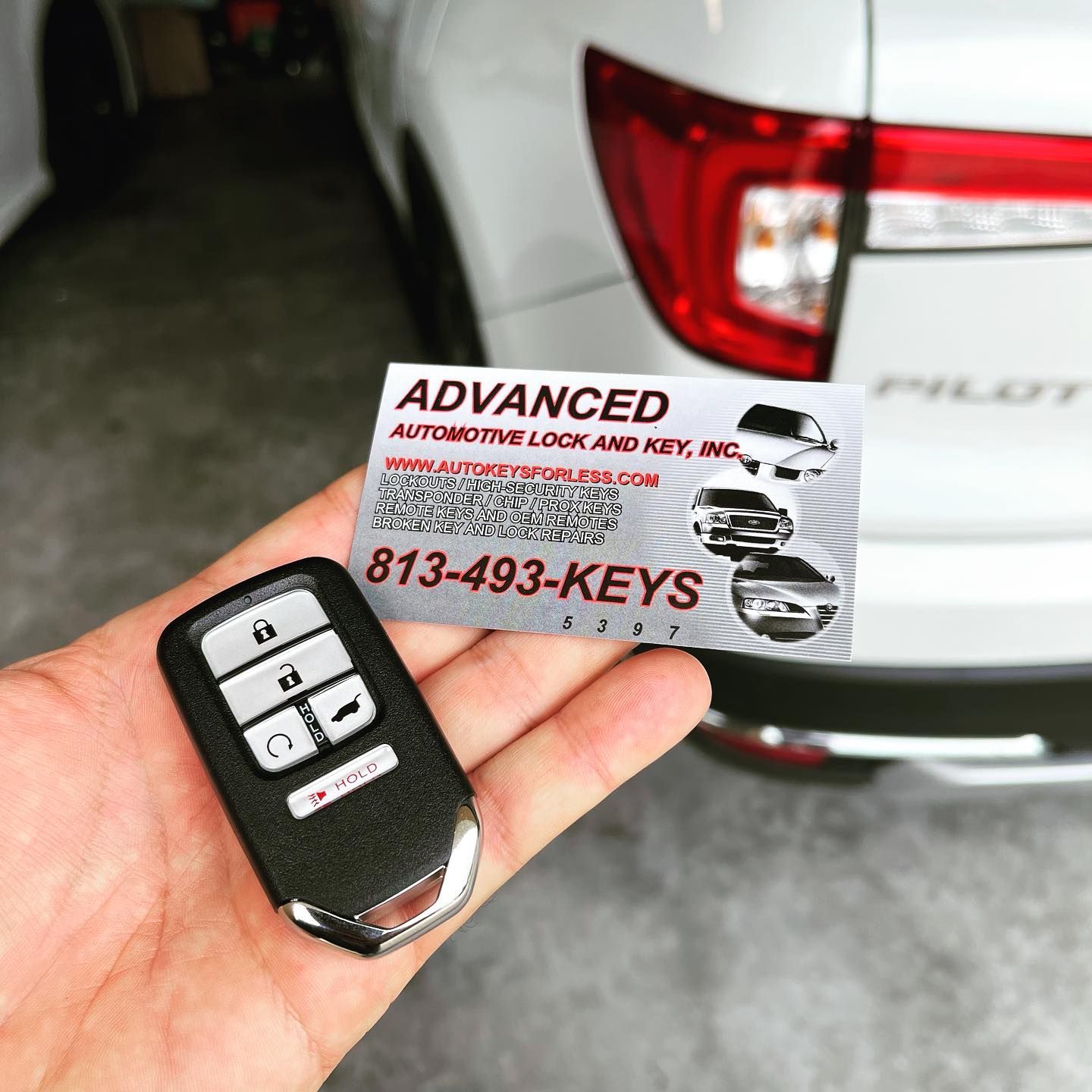 A person is holding a car key in front of a white car