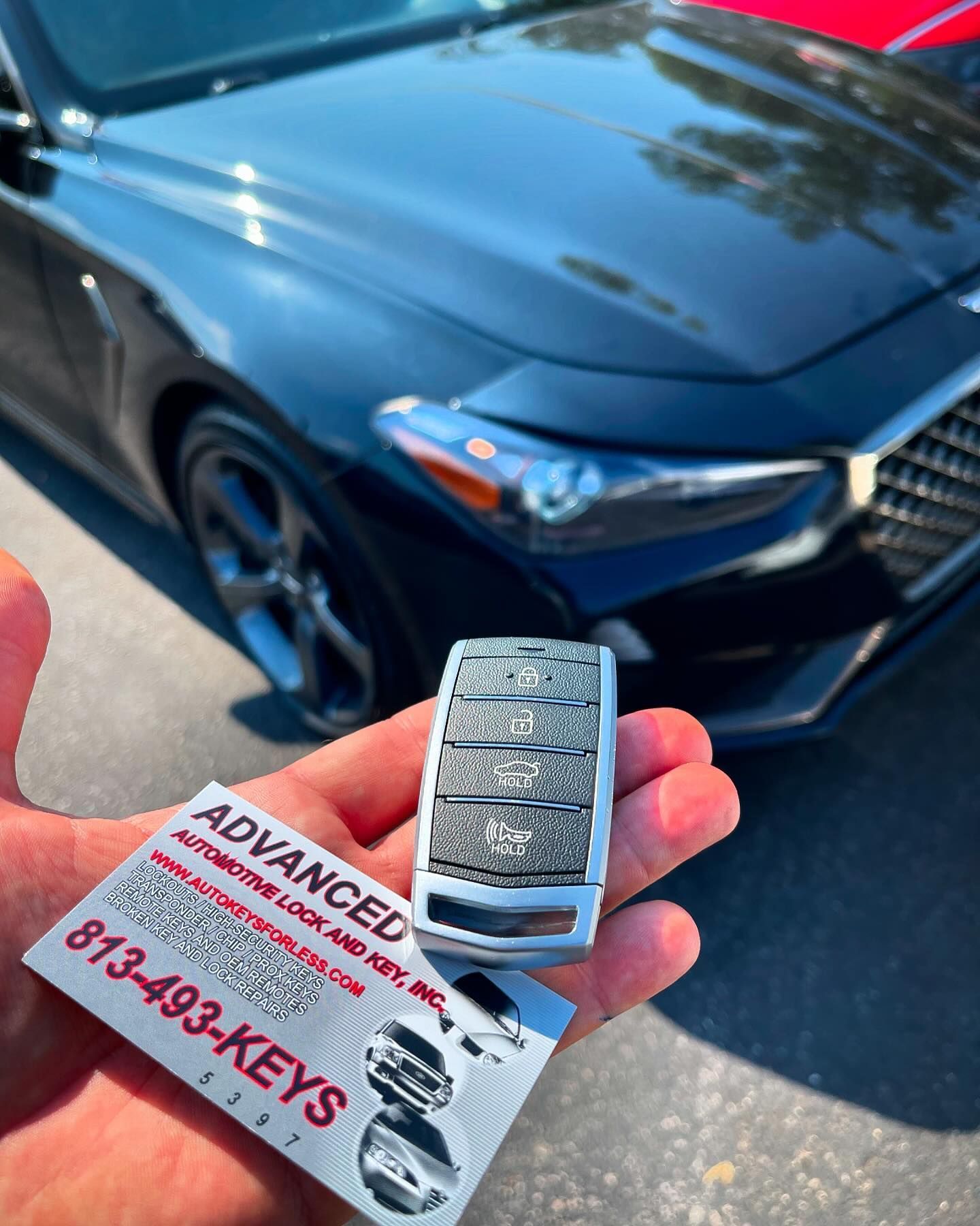 A person is holding a car key in front of a car.