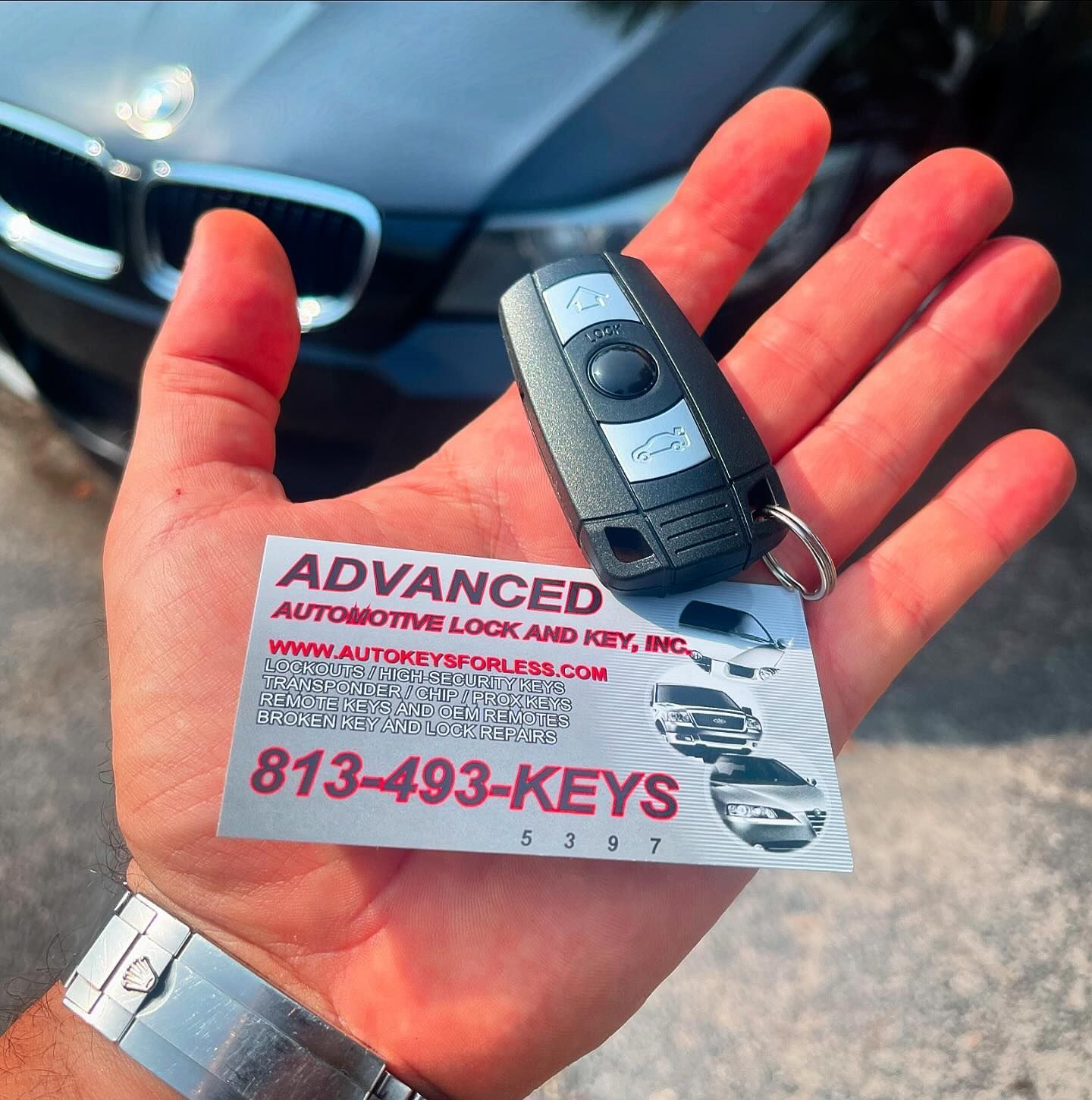 A person holding a car key in front of a bmw
