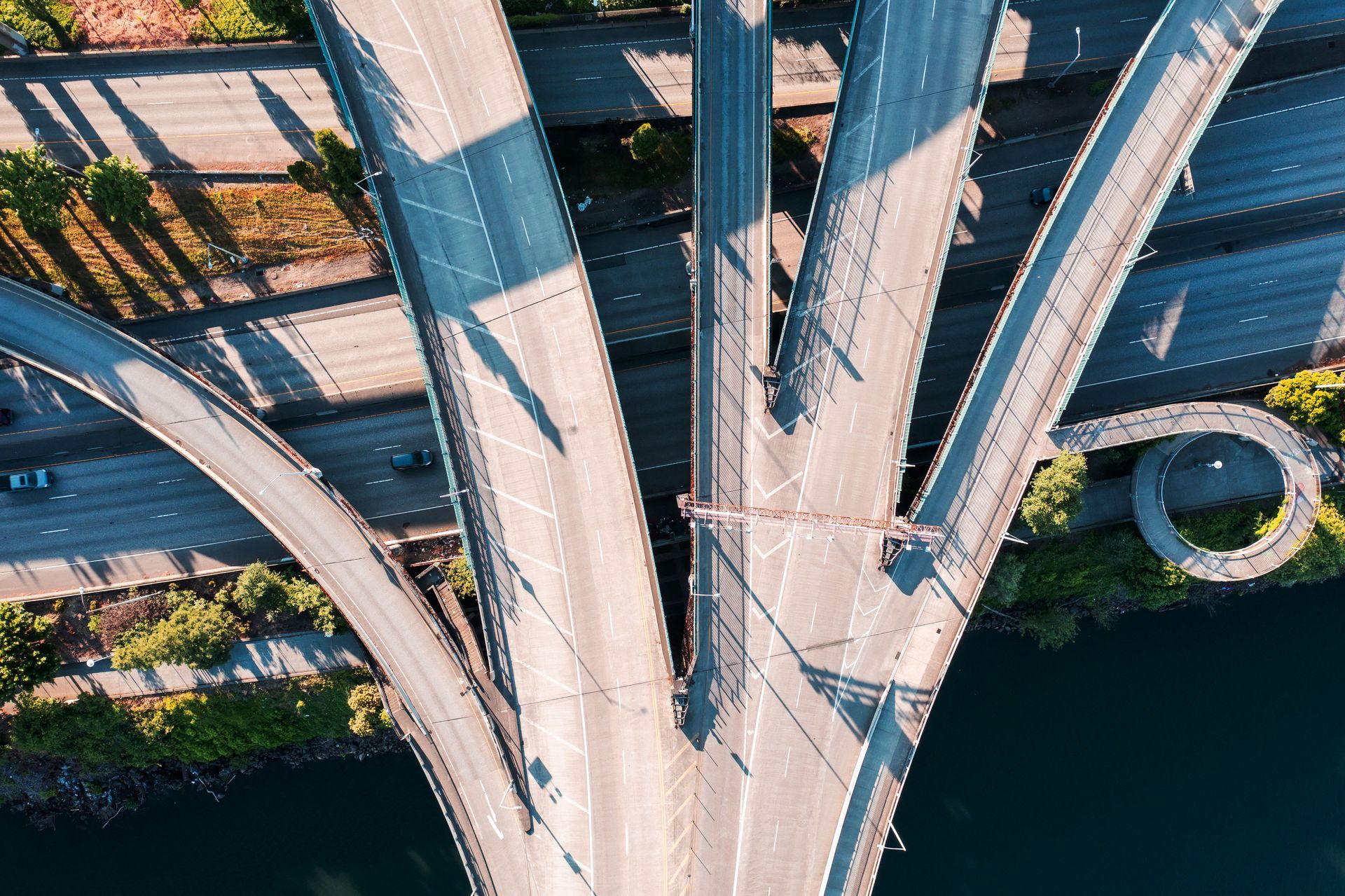 Aerial view of a multi-lane highway interchange crossing over dark water and greenery.