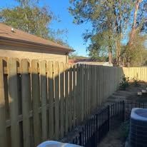 Wooden fence surrounding a house with a blue sky.