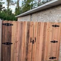 Wooden gate with black hardware in front of a brick wall.