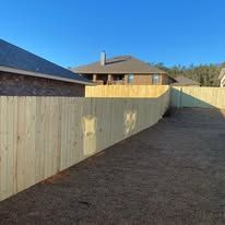 Wooden fence in front of a house on a sunny day.
