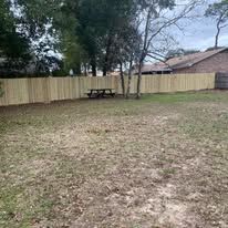 Wooden fence encloses a grassy backyard with a picnic table.