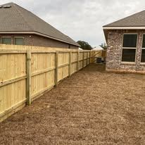 Wooden fence bordering a backyard with houses in background.