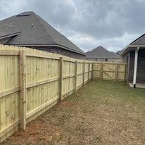 Wooden fence in backyard. House in background. Grassy yard. Overcast sky.