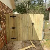 Wooden gate with black hardware in a yard.