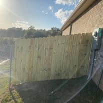 Wooden fence next to a building; sunny outdoor setting.
