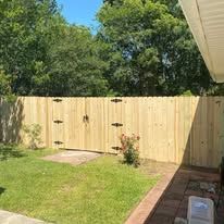Wooden fence with black hinges and a grassy yard.