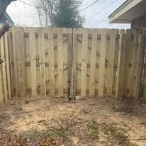 Wooden fence with a gate in a grassy outdoor setting.