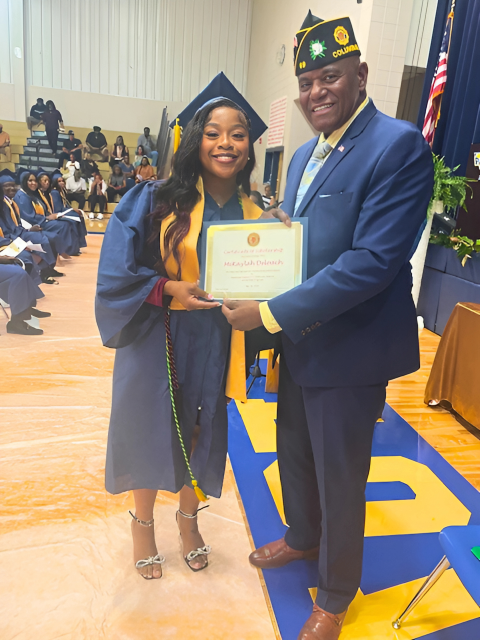 Robert Bishop s giving a certificate to a woman in a graduation cap and gown