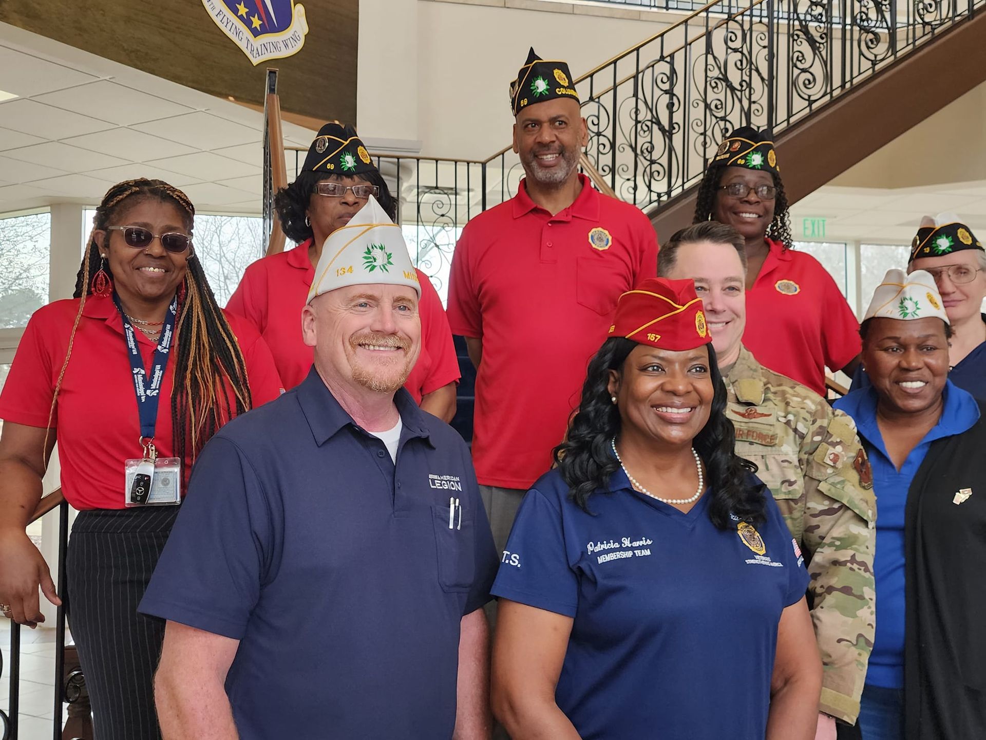 A group of American Legion Post 69 members posing for a picture in front of a staircase.