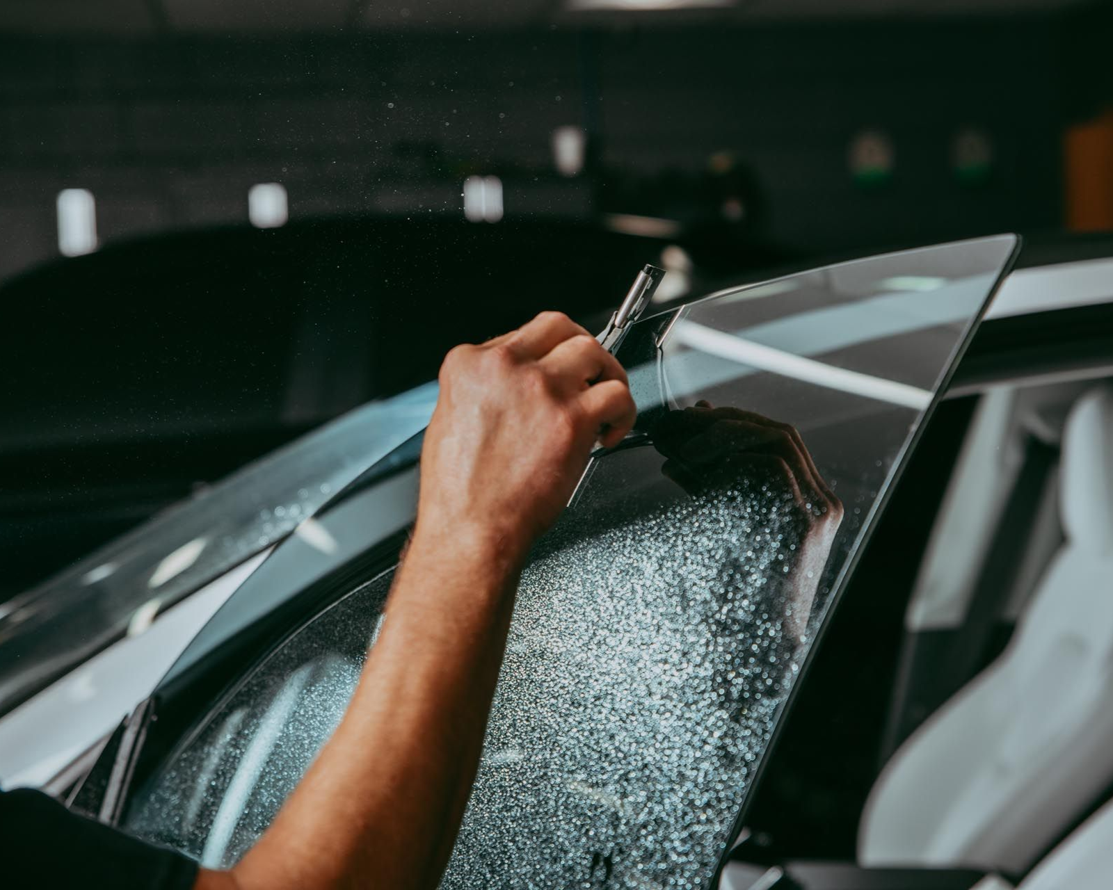 Person applying tint film to a car window.