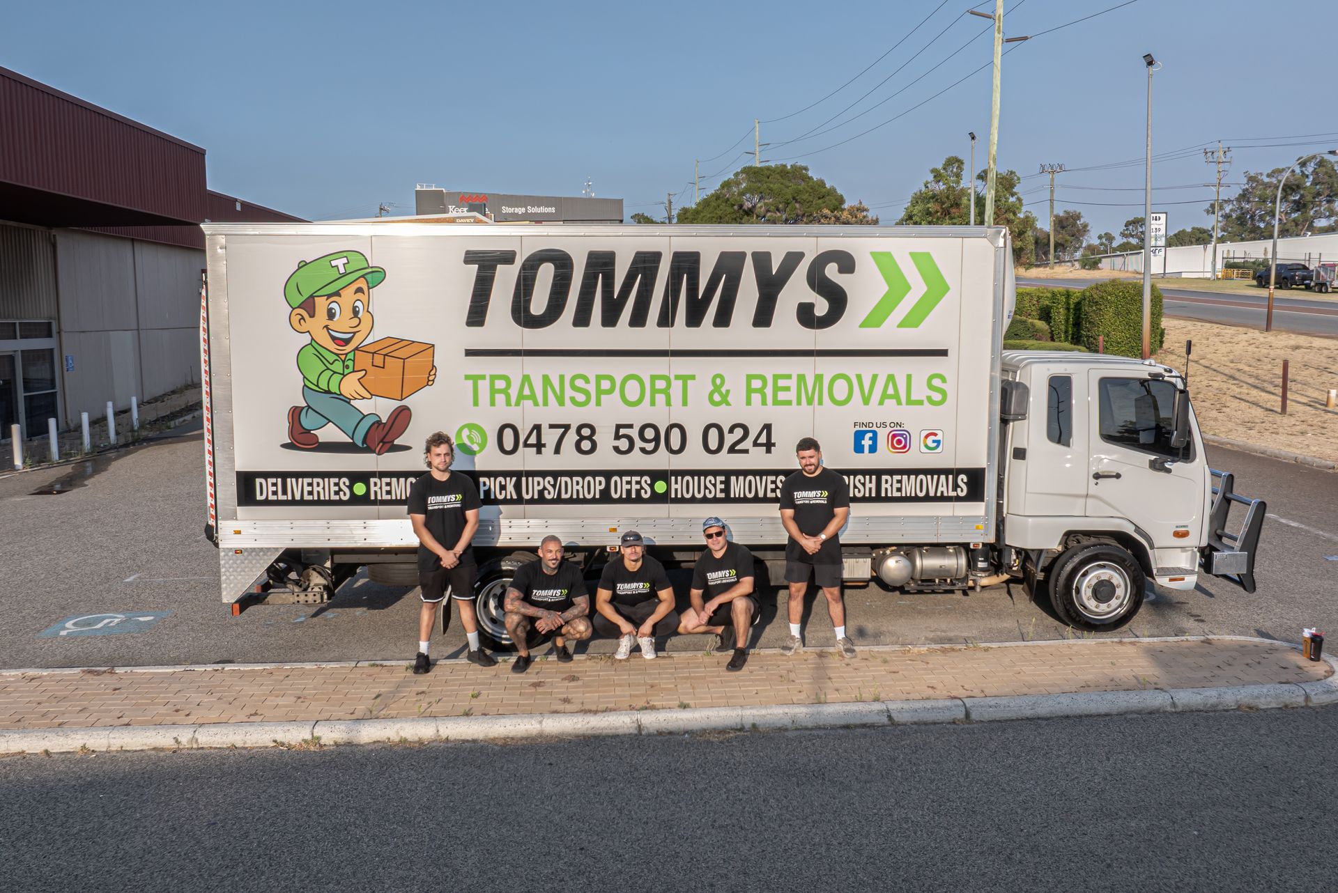 Five team members stand in front of a white 