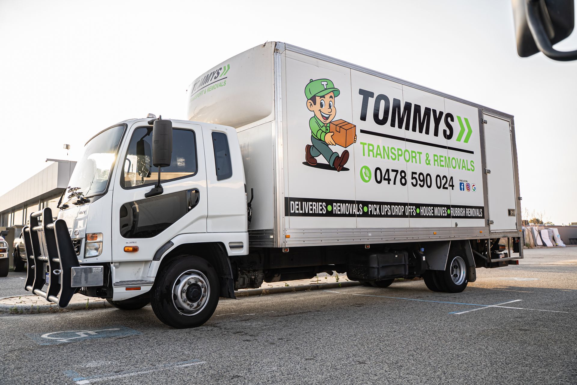 White Tommy’s removal truck parked outdoors, with company logo and contact details on the side.