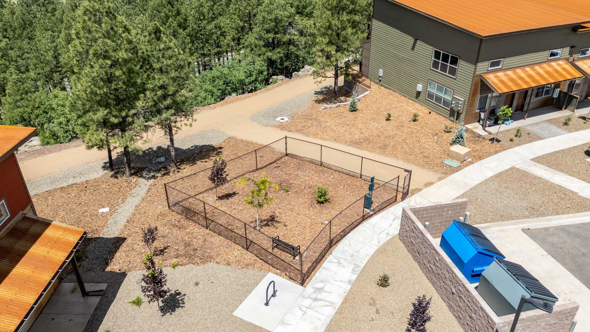An aerial view of a dog park with a fence and a building in the background.