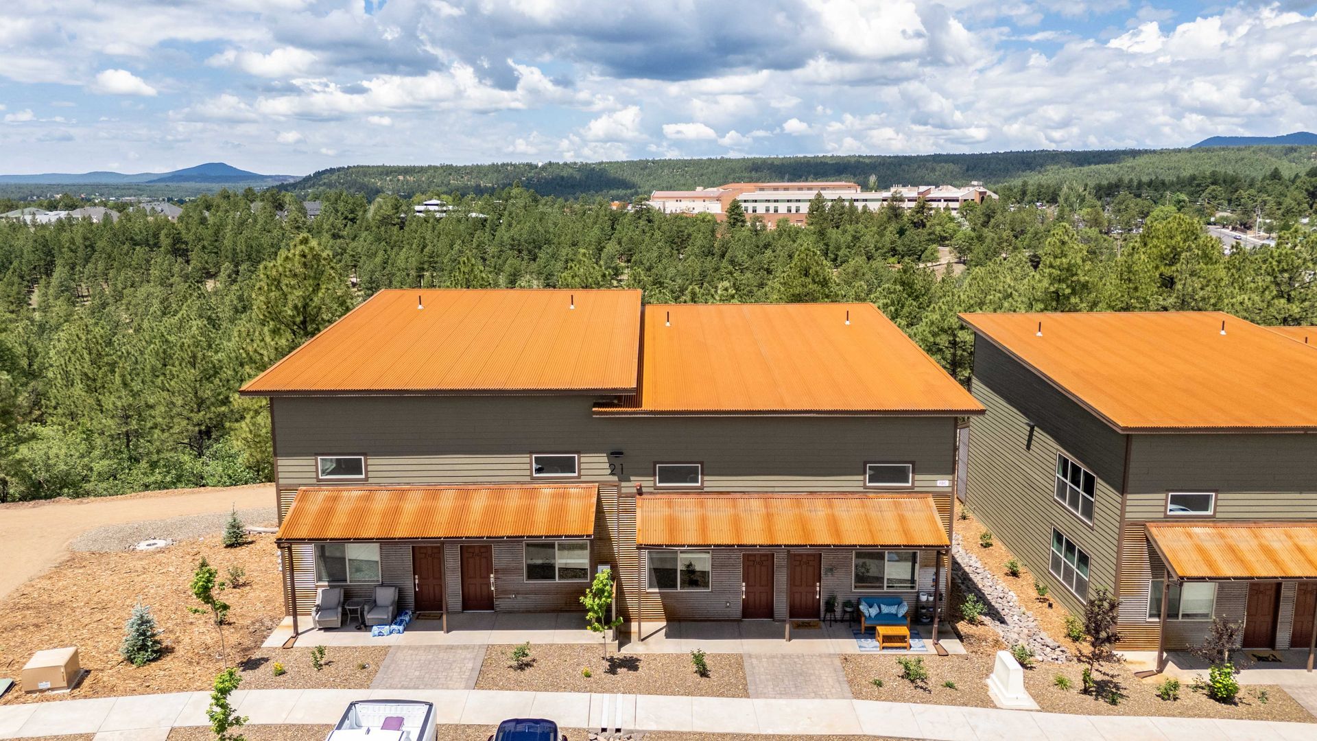An aerial view of a row of houses with a lot of trees in the background.