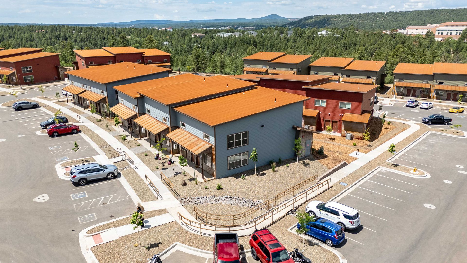 An aerial view of a parking lot with cars parked in front of a building.
