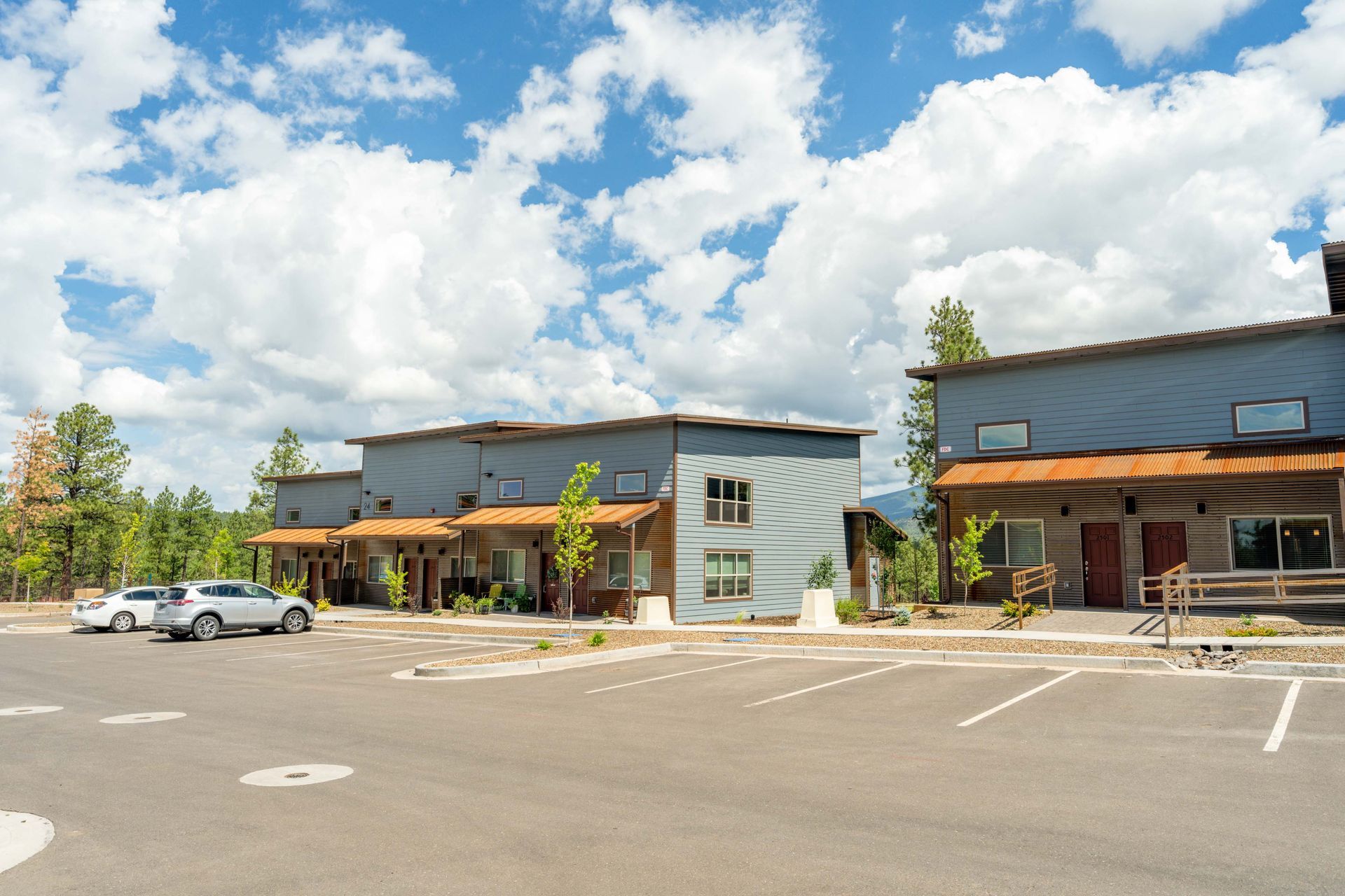 A parking lot with cars parked in front of a row of buildings.