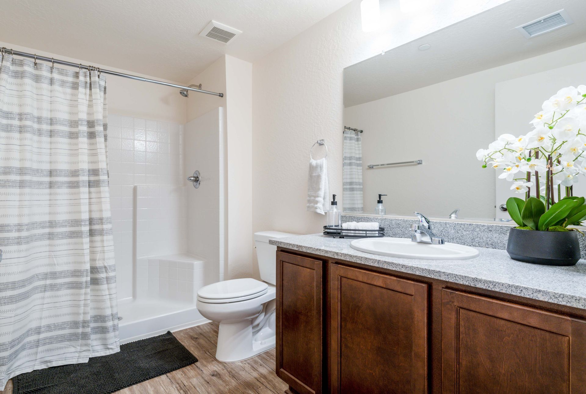 A bathroom with a toilet , sink , shower and mirror.