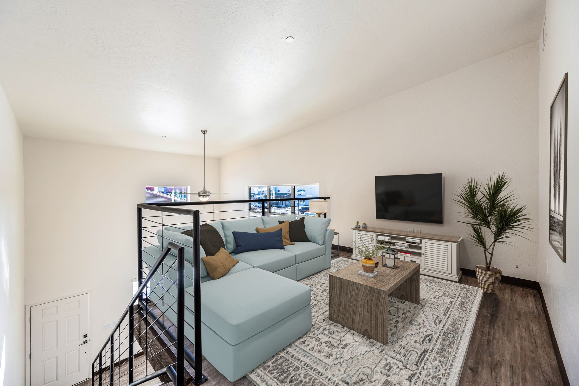 A living room with a couch , coffee table , television and stairs.