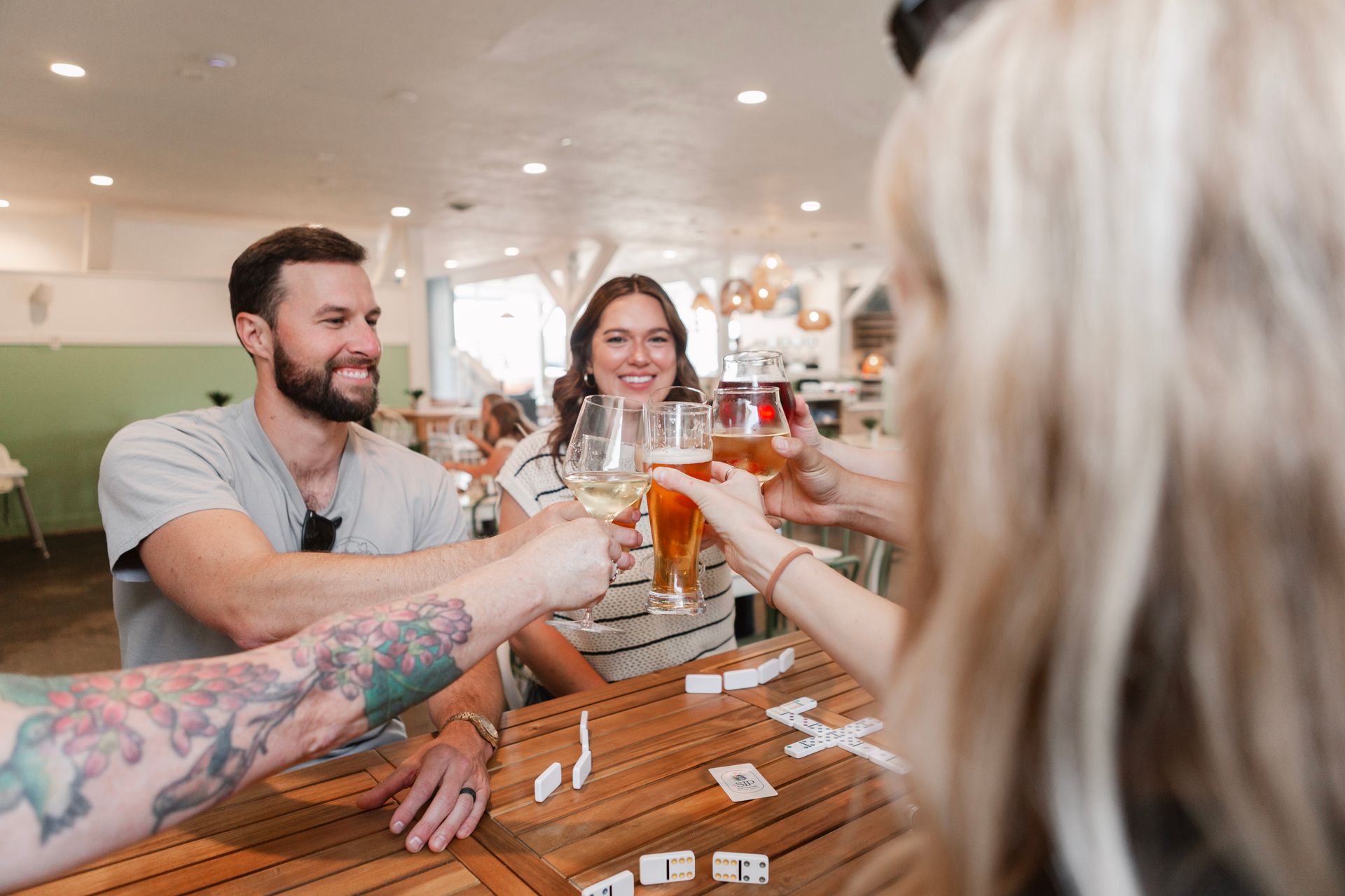 A group of friends sharing a cheers over a game of dominoes at The Sip