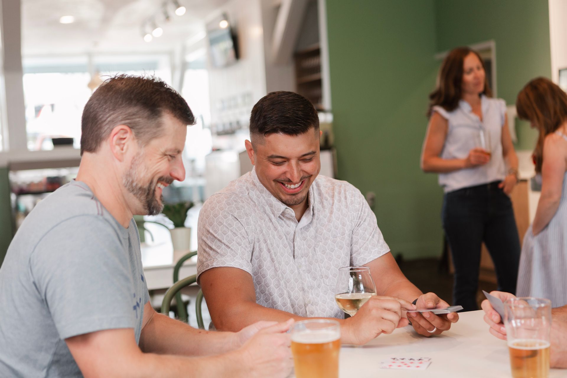 A couple of friends enjoying their self-pour beers and a card game at The Sip in Poulsbo.