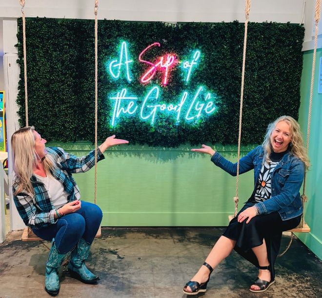 Image of two ladies sitting on swings in front of 