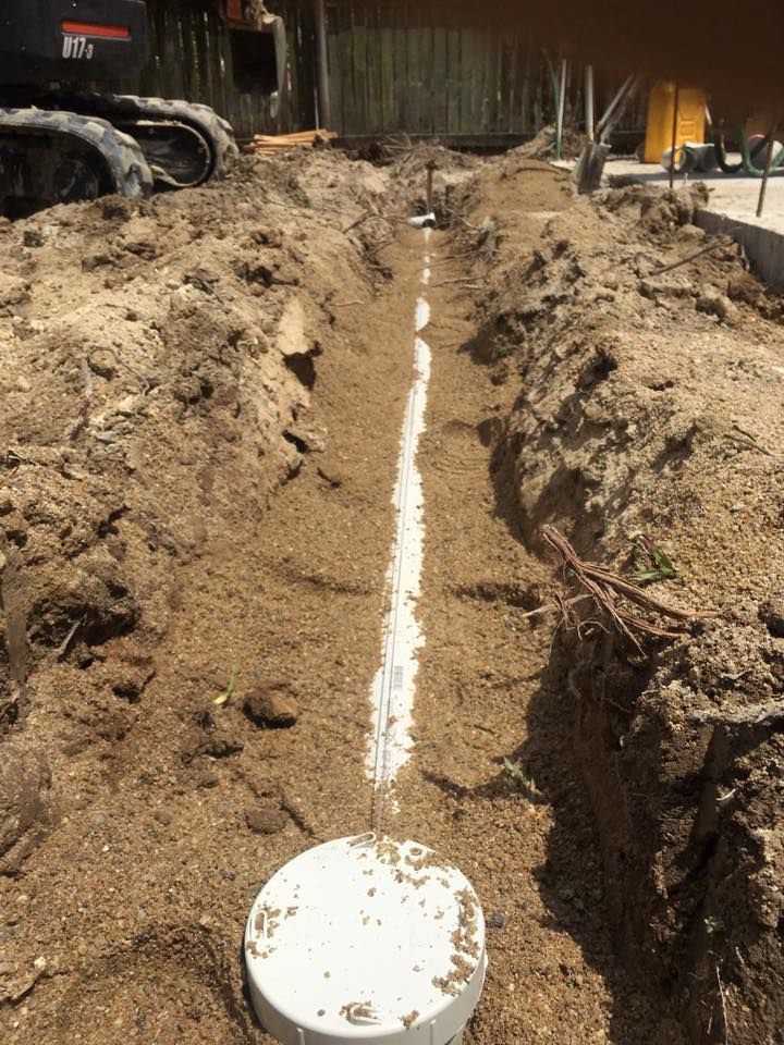 Trench Dug in Dirt With White Pvc Pipes, Likely for Plumbing — Langley Plumbing in Mareeba, QLD