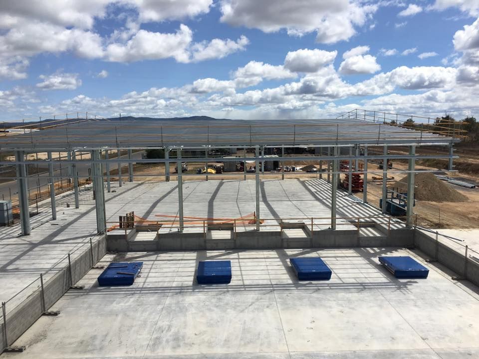 Construction site with steel framework and concrete foundation under a cloudy sky — Langley Plumbing in Mareeba, QLD