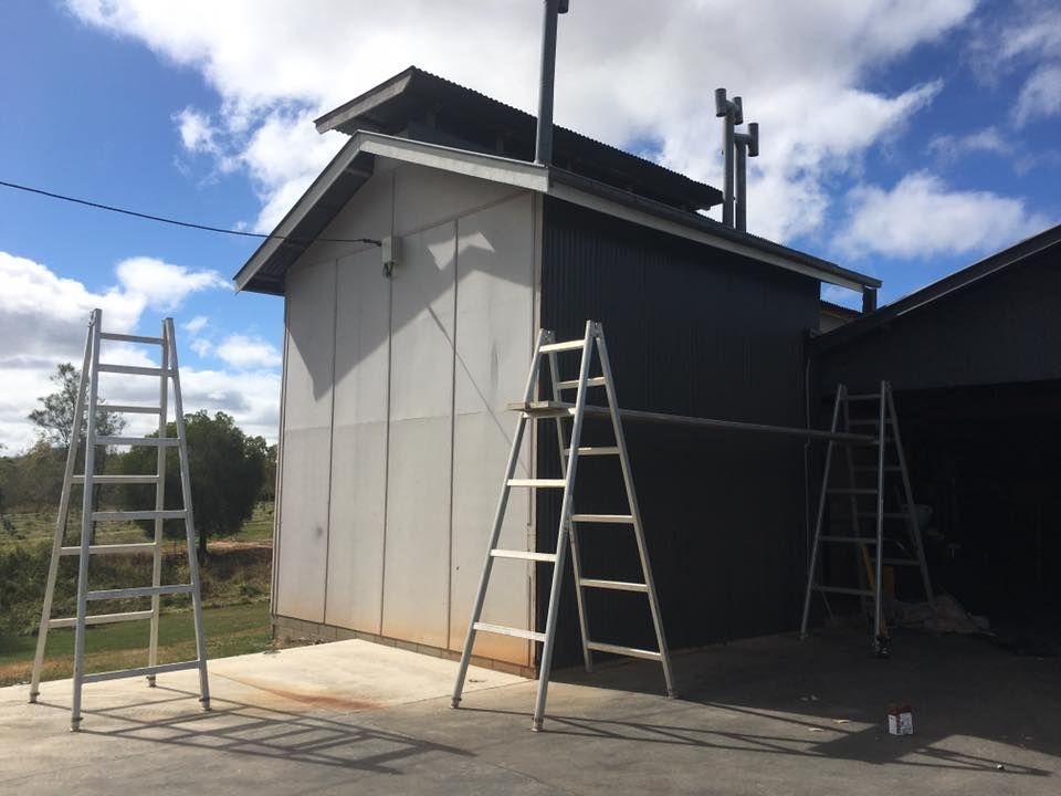 Building With Gray and Black Siding, Multiple Ladders, and Chimneys — Langley Plumbing in Mareeba, QLD
