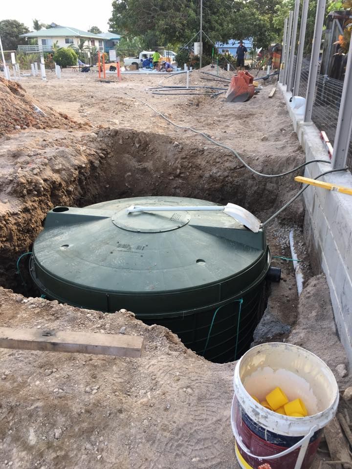 A Dark Green Water Tank Partially Buried in a Construction Site — Langley Plumbing in Mareeba, QLD