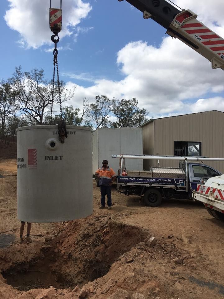 A Concrete Tank Being Lifted by a Crane Into a Dug Hole — Langley Plumbing in Mareeba, QLD