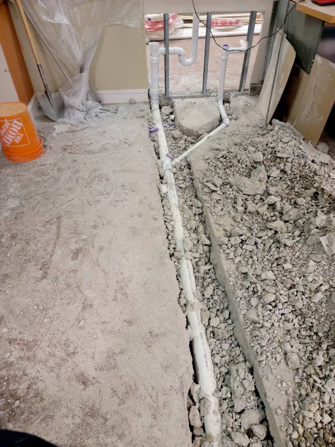 Trench with a pipe running through it, piles of dirt on either side, and utility poles in a construction zone.