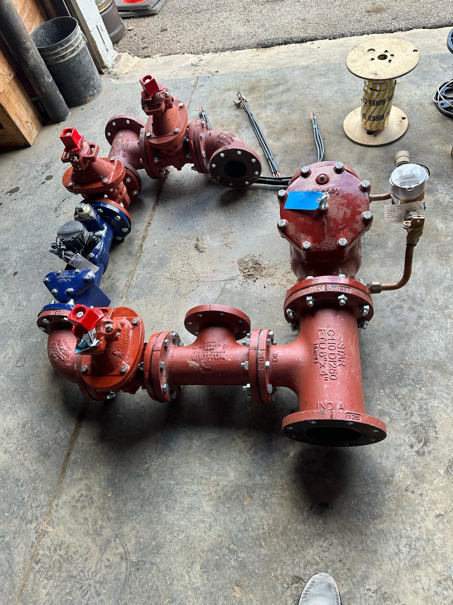 Red and blue industrial valves arranged in a loop on a concrete surface.