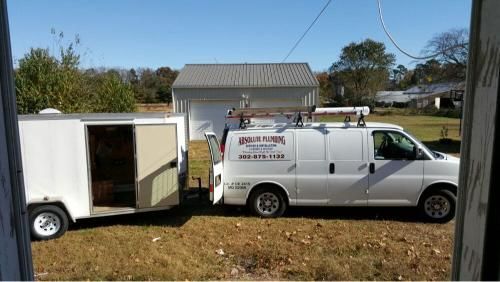 White van with a trailer, parked in a yard; clear day.