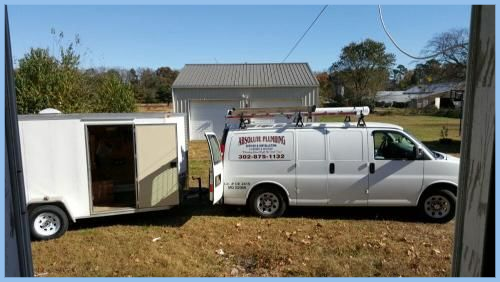 White plumbing pipes under a sink, with a gray hose and visible connections.