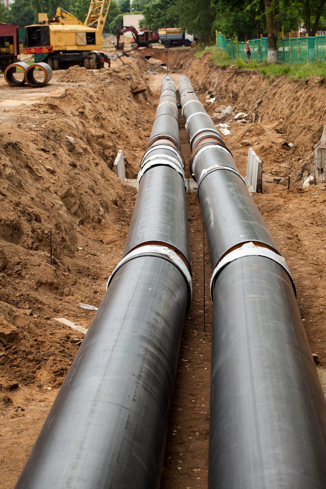 Blue and black water pipes with a valve, buried in dirt.